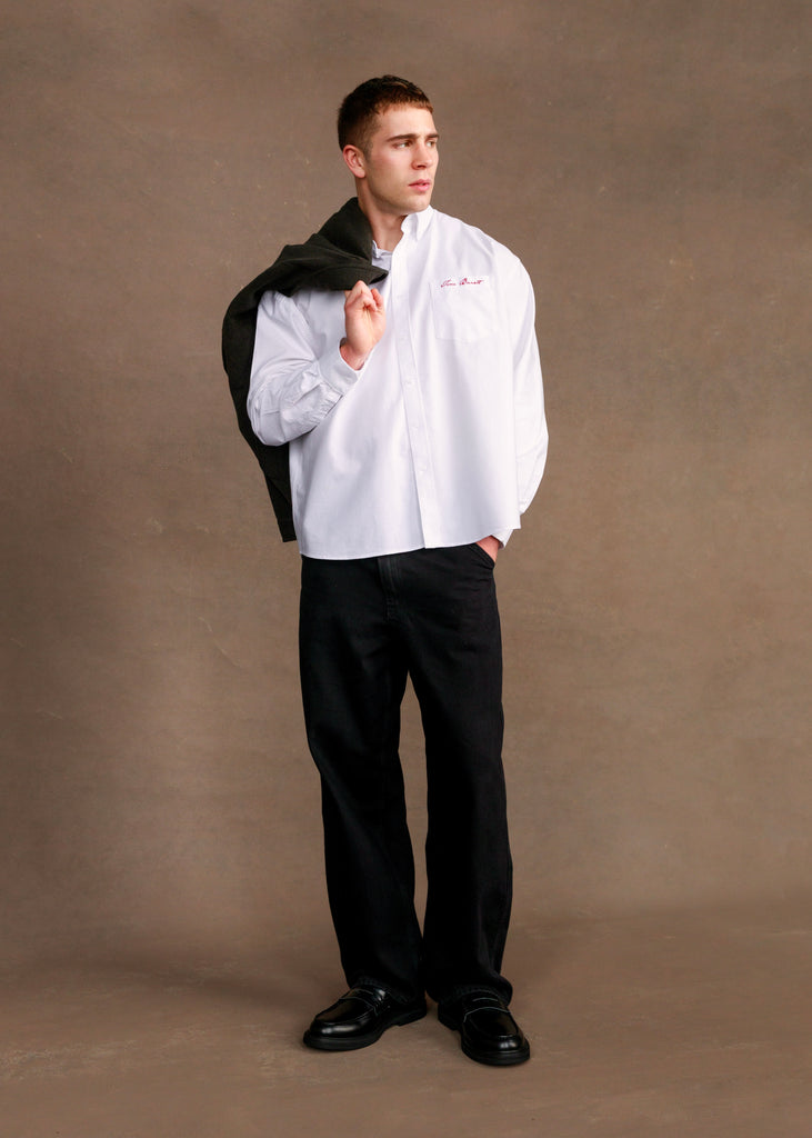 Man wearing a white shirt and black pants against a brown background